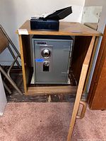 Brinks Home Security Safe inside a wooden cabinet with door open; cash drawer on top.