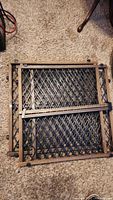 Two black plastic lattice gates with wooden frames folded and placed on carpet