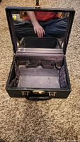 Open black faux leather jewelry box showing interior compartments and attached mirror.