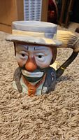 Front view of the Emmett Kelly Jr clown ceramic cup showing facial detail and paintbrush handle.
