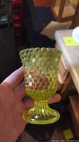 Front and side view of yellow hobnail glass candle holder held in hand