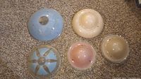 Five vintage glass light covers on carpet showing colors and mounting hole details