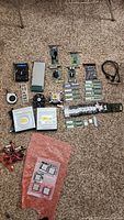 Overview of all computer parts laid on carpet, showing CPUs, RAM, optical drives, fans, and expansion cards
