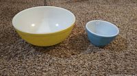 Yellow and blue Pyrex bowls side by side on carpet showing color and interior.
