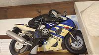 Side view of Suzuki GSX-R remote control motorcycle with rider figurine and handheld remote control showing buttons and antenna.