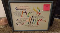 Front view of the framed wall art showing the colorful calligraphy text 'Be Alive' and a poem or text.