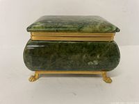 Front view of the closed green marble jewellery box showing its smooth polished surface and gold trim base and lid edge.