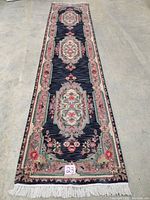 Full view of the runner rug laid on the floor showing three medallions and floral border with fringed ends.