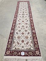 Full-length view of ivory and burgundy floral hand-knotted runner on concrete floor