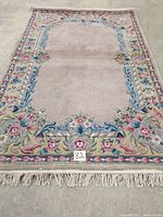 Full view of the hand tufted Savonnerie rug showing floral border and fringed edge.