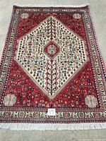 Full view of rectangular rug with central cream hexagonal medallion, red field, ivory fringe on ends