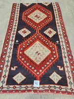 Full view of the Persian hand knotted Songhor carpet laid flat on the floor showing overall pattern and fringe on one side.
