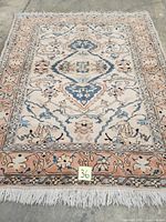 Full view of the Persian carpet showing central medallion, borders, and fringed ends.