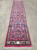 Full-length view of pink Persian runner laid flat, showing overall pattern, border and fringed ends