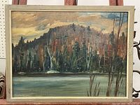 Full view of framed oil painting showing a landscape scene with water and forested hill under cloudy sky.