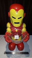 Front view of 21 inch tall Iron Man figurine holding a clear glass bowl with measurement scale beside.