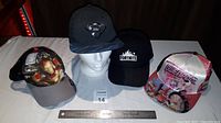 Front view of four hats including Superman, Iron Man, Fortnite, and pink superhero design.