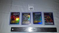Photo of the front side of the four Digimon cards with ruler for size reference, showing holographic details and artwork including Imperial Dramon.