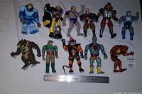 Top view of 12 vintage Thundercats action figures laid out on white background with ruler for scale.