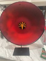 Frontal view of red glass dish mounted on black metal stand