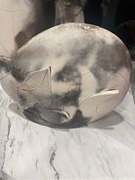 Photo showing bottom of pottery cat sculpture with smoky black and white finish and etched geometric details.