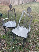 Pair of metal Lena accent chairs with a contemporary design, showing overall condition and style outdoors on grass.