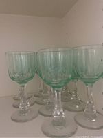 Set of 12 green tinted stemmed glasses viewed from front and side angles showing texture and shape.