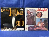 Two vinyl record sleeves side by side on blue fabric background showing Earl Fatha Hines and Jackie Opel albums.