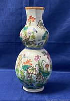 Front view of double-gourd vase showing hand-painted lotus flowers and birds on white porcelain surface.