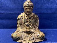 Front view of bronze Buddha sculpture showing worn gold paint and meditation posture