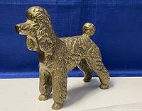 Front angled view of solid brass Standard Poodle figurine revealing detailed fur texture and stance.