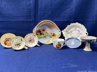 Full set of various chinaware pieces including Limoges serving dish, Wedgwood dish, orphan teacups with floral and fruit motifs, and scalloped plates.
