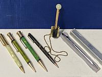 Overview of four Parker mechanical pencils, brass desk pen holder and two boxed Cross pens on white background