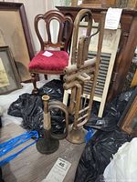 Two antique brass horn instruments placed upright near furniture and other items.