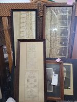 Five frames displayed grouped against a couch; includes large and panoramic group photos and a portrait with dark wooden frames showing wear.