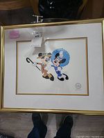 Framed serigraph of Mickey and Minnie Mouse, approximately 17x20 inches, matted and framed in gold.