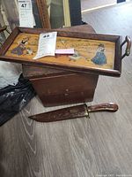 Antique hinged wooden box, painted wooden tray with handles, and wooden-handled knife with carved sheath placed on the floor. Shows condition and relative scale.