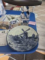 Top view of the blue and white Delft decorative plate with windmill design, along with creamer and figurine on a blue table.