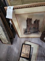 Framed cathedral print with ornate gold-tone frame, leaning against wall, showing signs of age and wear.