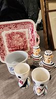 Photo showing the red and white Mason's Ironstone platter, Lambrecht butter crock, Alcatraz prisoner salt and pepper shakers, and vintage egg cups arranged on floor.