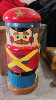 Front view of the painted wooden soldier figure showing the detailed face, red hat with gold star, and colorful uniform.