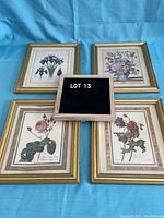 Four floral still life prints in gold frames laid out on blue background with a lot number sign