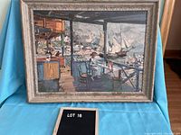 Framed reproduction painting showing waterfront scene with woman sitting on porch, sailboats in background