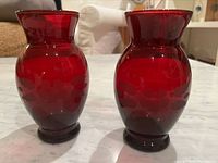 Pair of matching vintage 1960s red glass vases with etched flower design displayed side by side on table.