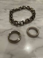 Photo of the stainless steel heavy link bracelet and two Calvin Klein Jeans stainless steel rings on a marble surface.