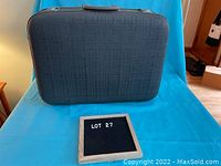 Front view of charcoal grey suitcase with textured exterior, showing overall shape and handle