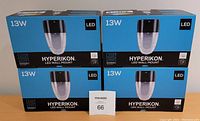 Four boxed Hyperikon LED Wall Mount lights showing 13 watt rating and product branding on blue and black packaging.