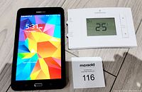 Samsung Galaxy Tab 4 Nook 7-inch tablet and Emerson thermostat side by side powered on.