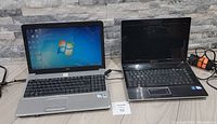 Front view of two laptops powered on and off, HP showing Windows 7 screen, Gateway powered off