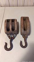 Top view of two wooden blocks with metal hooks, showing two sheaves on left block and one sheave on right block.